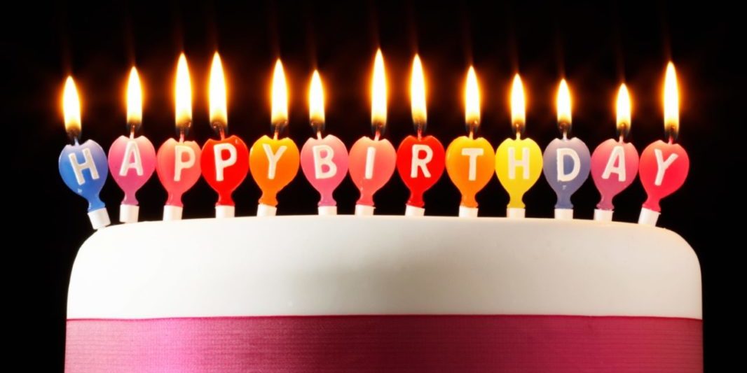 Iced cake lit with happy birthday candles