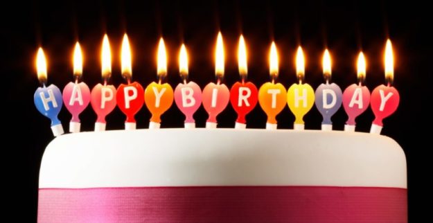 Iced cake lit with happy birthday candles